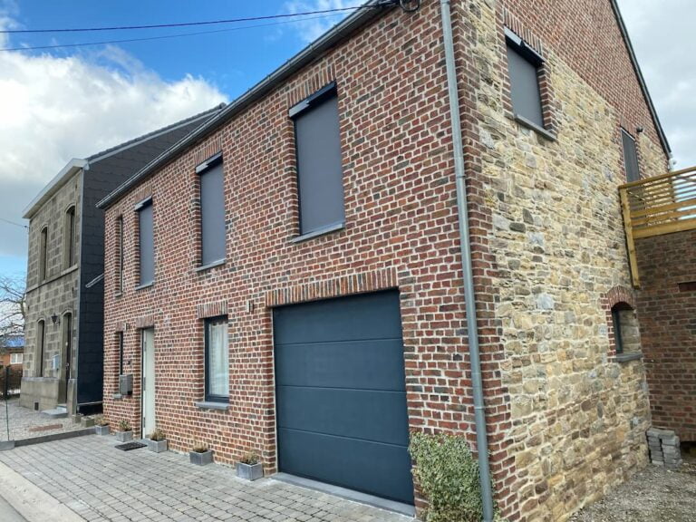 Screens solaires gris anthracite sur fenêtres du premier étage d'une maison en brique