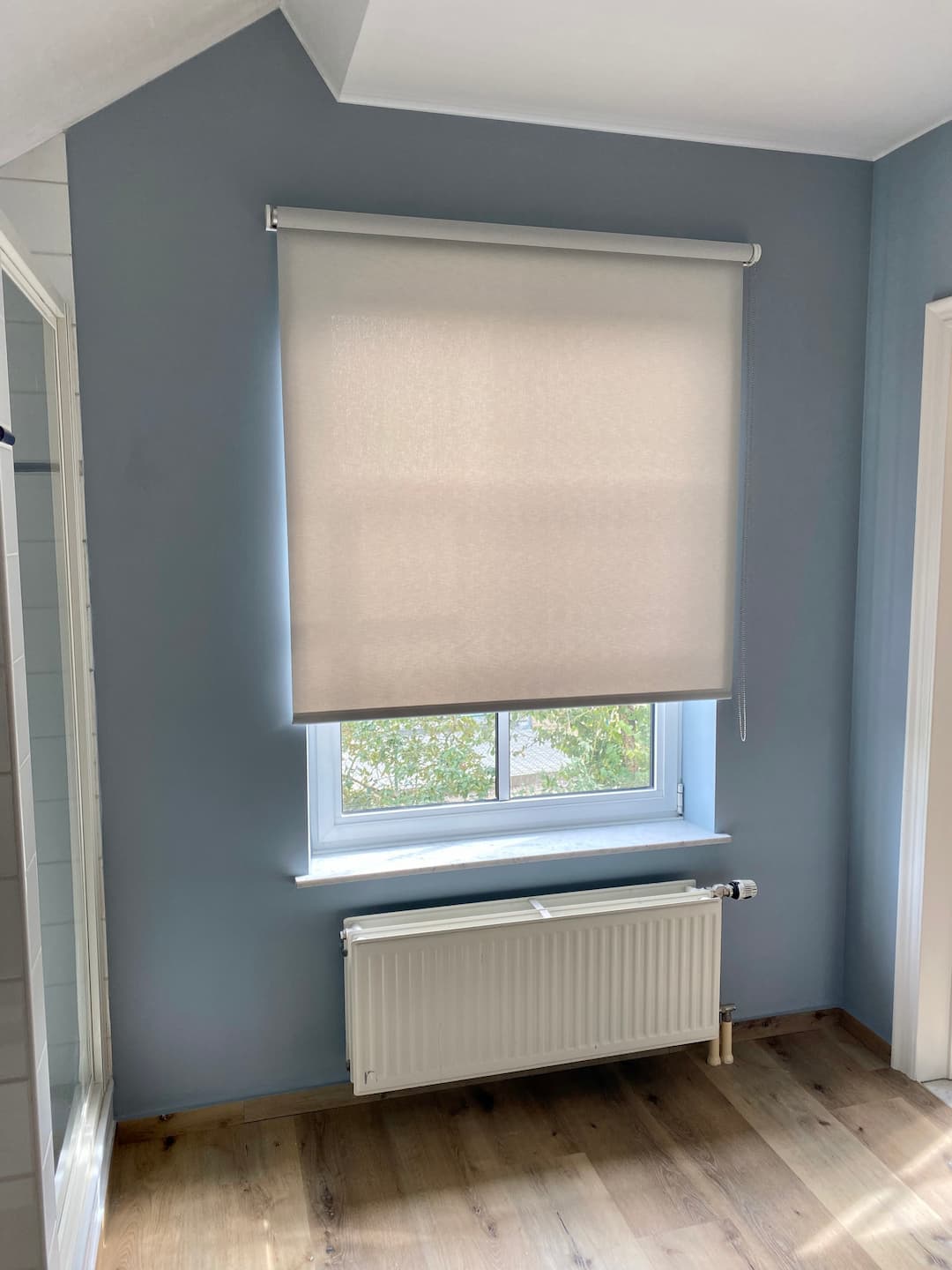 Store enrouleur blanc dans une salle de bain aux murs bleu clair